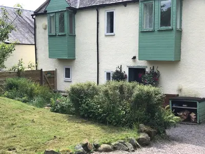 a house with green shuttered windows and a yard at Corlae Cottage, mountain and forest views in Carsphairn