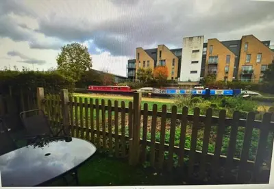 a fence with a table and a train in the background at Grebe House in Moffat