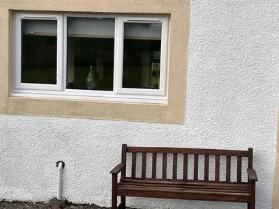 a wooden bench sitting in front of a window at Williamsfield Cottage in Holywood