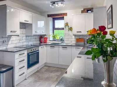 a kitchen with white cabinets and a vase of flowers at Cottage At Brathen in Penrith