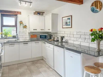 a kitchen with white cabinets and a counter top at Cottage At Brathen in Penrith