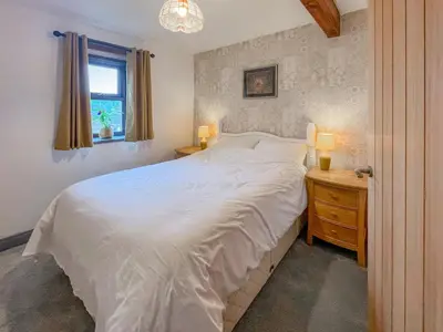a bedroom with a bed and a night stand with two lamps at Cottage At Brathen in Penrith