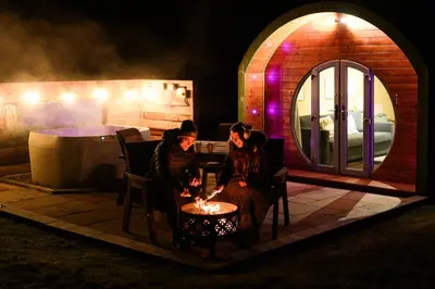 two women sitting around a table with a candle at Barnharrow Holiday Pods - Rose Glamping Pod with Hot Tub & Fire Pit in Balminnoch