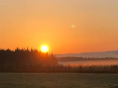 a sunset with the sun setting over a field at Barnharrow Holiday Pods - Rose Glamping Pod with Hot Tub & Fire Pit in Balminnoch