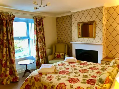 a bedroom with a bed and a fireplace and a window at The MireHouse - Georgian rural retreat in Ullock