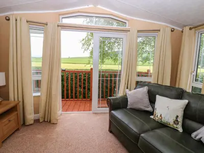 a living room with a couch and a balcony at 12 Field View in Carlisle