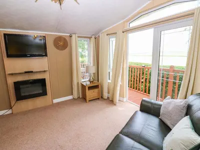 a living room with a couch and a television and a balcony at 12 Field View in Carlisle