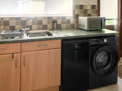 a kitchen with a sink and a washing machine at Rubby Banks Retreat in Cockermouth