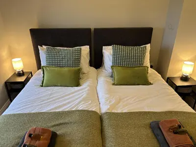a bedroom with two beds with green pillows at Swirral Edge Cottage in Penrith