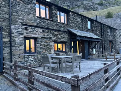 a stone house with a table and chairs in front of it at Swirral Edge Cottage in Penrith