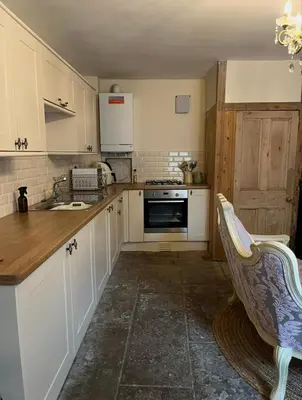 a kitchen with white cabinets and a sink at Sycamore Cottage - Lake District Hiking & Rivers in Cockermouth