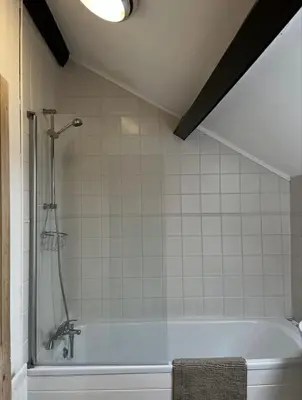 a bathroom with a bath tub with a shower at Sycamore Cottage - Lake District Hiking & Rivers in Cockermouth