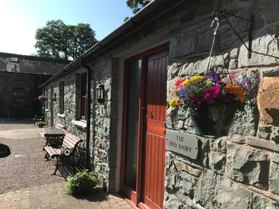 a stone building with a red door and flowers on it at Castlehead Cottage in Keswick