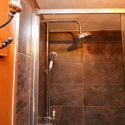 a shower with a shower head in a bathroom at Tranquil Lake District Village Apartment in St Bees