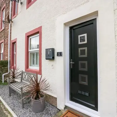 a black door with a bench next to a building at Tranquil Lake District Village Apartment in St Bees
