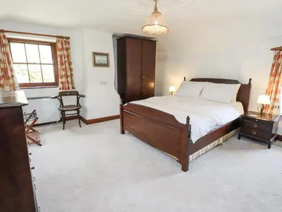 a bedroom with a bed and a chair and a window at Chapel Cottage in Cleator