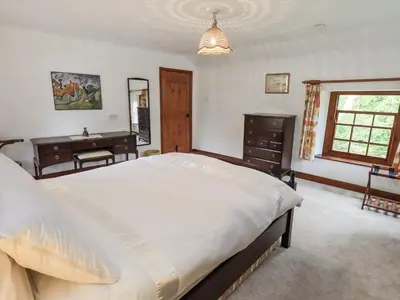 a bedroom with a large bed and a desk at Chapel Cottage in Cleator