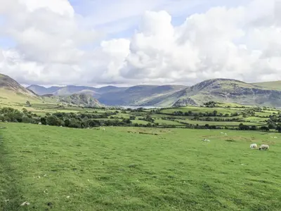 a green field with sheep grazing in the mountains at Chapel Cottage in Cleator