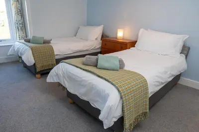 a room with two beds and a dresser with a lamp at Larroch Farmhouse in Monreith