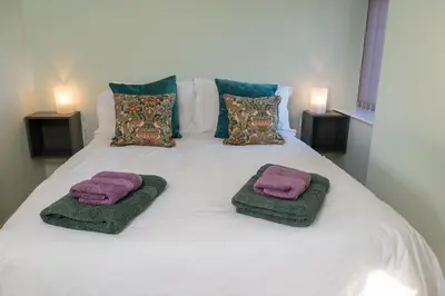 a white bed with two purple towels on it at The Larroch Byre in Monreith