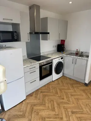a kitchen with white cabinets and a washer and dryer at Stylish Flat in City Center in Moffat