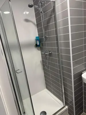 a shower with a glass door in a bathroom at Stylish Flat in City Center in Moffat