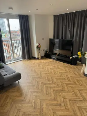 a living room with a flat screen tv and a wooden floor at Stylish Flat in City Center in Moffat