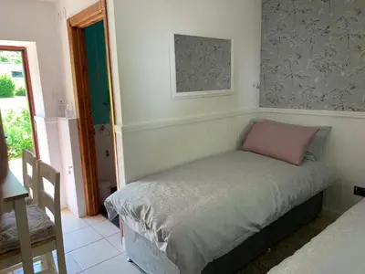 a small bed with a pink pillow in a room at Whitestone Cottage in Turnberry