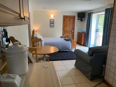 a living room with a bed and a table at Whitestone Cottage in Turnberry
