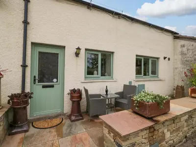 a house with a green door and a patio at Yeat Stoup Cottage in Cockermouth