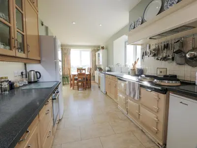 a large kitchen with wooden cabinets and a large island at Claymoddie in Newton Stewart