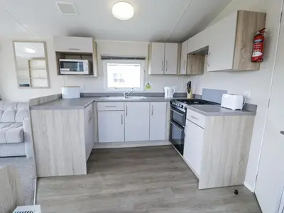 a small kitchen with white cabinets and a sink at Manor House Gold 2 Bedroom 20C in Maryport