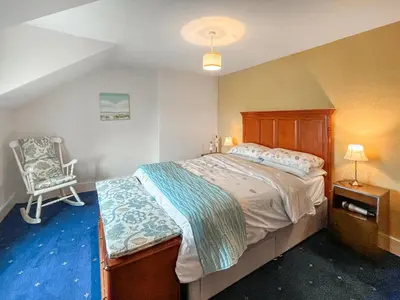 a bedroom with a large bed and a chair at The Haven in Annan