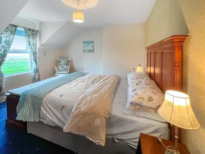 a bedroom with a bed and a lamp and a window at The Haven in Annan