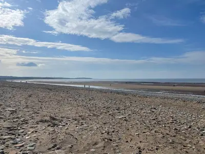 a beach with rocks and a blue sky and clouds at Sun House in Maryport