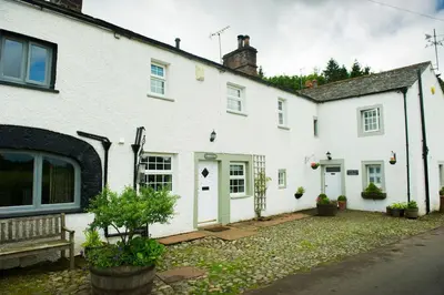 a white house with a bench in front of it at Charming cosy Lakeland cottage near Ullswater in Dacre