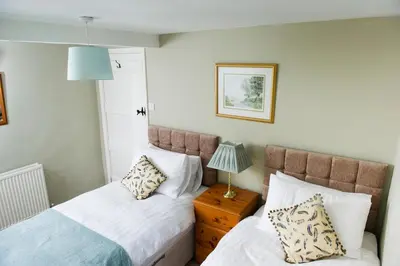 a bedroom with two beds and a lamp on a night stand at Charming cosy Lakeland cottage near Ullswater in Dacre