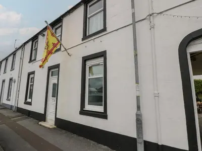 a white building with a flag on the side of it at King's Apartment in Castle Douglas