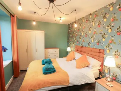 a bedroom with a large bed with green walls at 10 Keekle Terrace in Cleator Moor