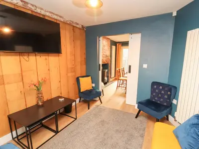 a living room with a table and chairs and a tv at 10 Keekle Terrace in Cleator Moor