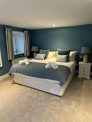a bedroom with a large bed with blue walls at Owl Cote in Girthon