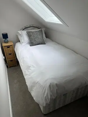 a bed with white sheets and pillows in a room at Owl Cote in Girthon