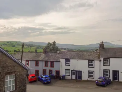 a row of houses with cars parked in front at Emilys Apartment, Ireby with fell views, ideal budget holiday for a family in Ireby