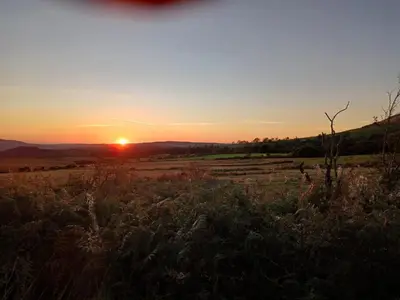 a field with the sunset in the background at Emilys Apartment, Ireby with fell views, ideal budget holiday for a family in Ireby