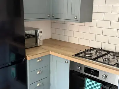 a kitchen with blue cabinets and a stove top oven at 2 bedroom cottage in Ayr