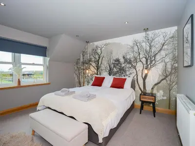 a bedroom with a large white bed and a window at Hill View at Kenmuir in Dalbeattie
