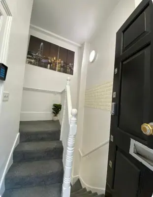a hallway with a staircase with a television and a stair case at Apartment in the heart of London in Moffat