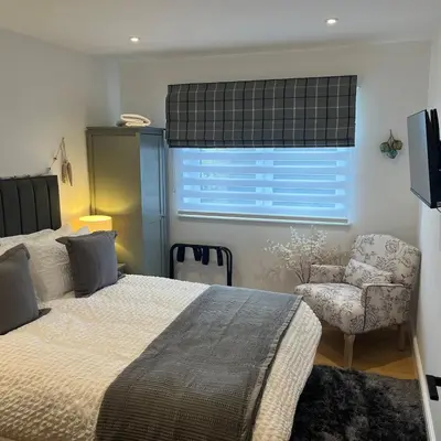 a bedroom with a bed and a chair and a window at The Fishermans Rest in Castle Douglas