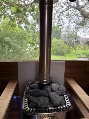 a black stove with rocks in front of a window at The Fishermans Rest in Castle Douglas