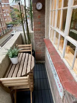 a bench sitting outside of a window with a clock at Elegant Chelsea Apartment in Moffat